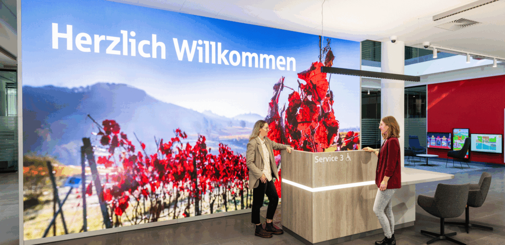 Große LED-Wand zur Kundenbegrüßung, im Hintergrund Displays im Wartebereich.